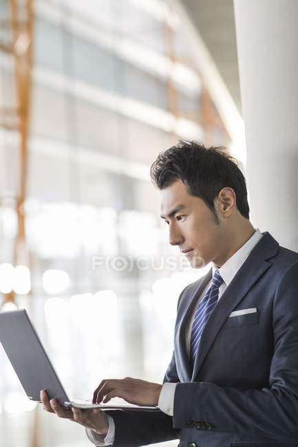 Китайский бизнесмен использует ноутбук в помещении — стоковое фото