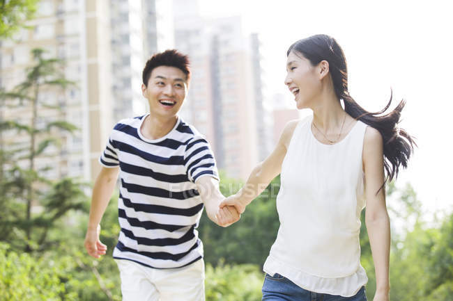 Junges chinesisches Paar hält Händchen beim Spazierengehen im Park — Stockfoto