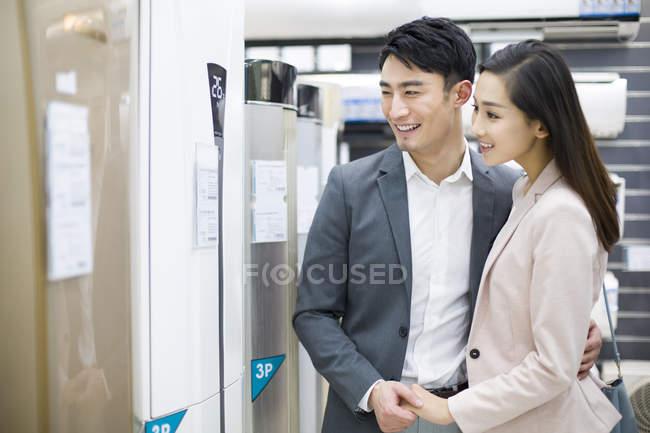 Chinese couple buying air conditioner in electronics store — Stock Photo
