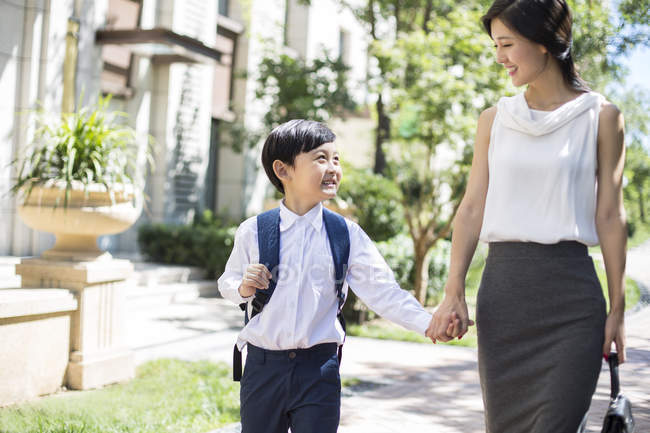 Chinese mother walking hand in hand with schoolboy — Stock Photo