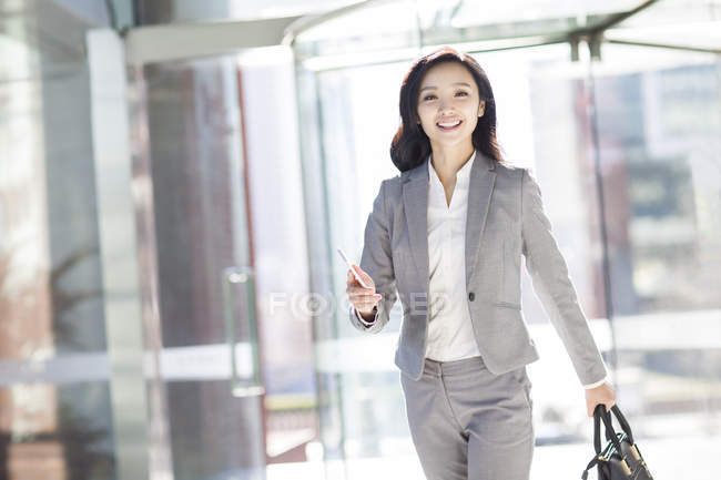 Азиатская деловая женщина, идущая со смартфоном — стоковое фото