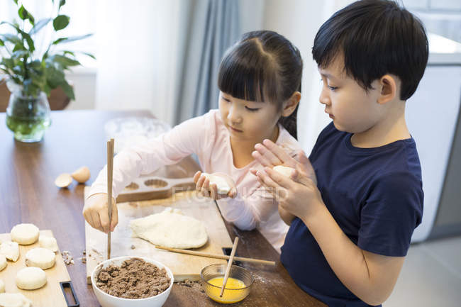 Hermanos chinos haciendo albóndigas en la cocina - foto de stock