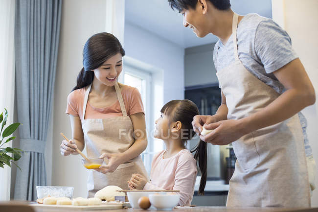 Chinesische Eltern mit Tochter backen gemeinsam in Küche — Stockfoto