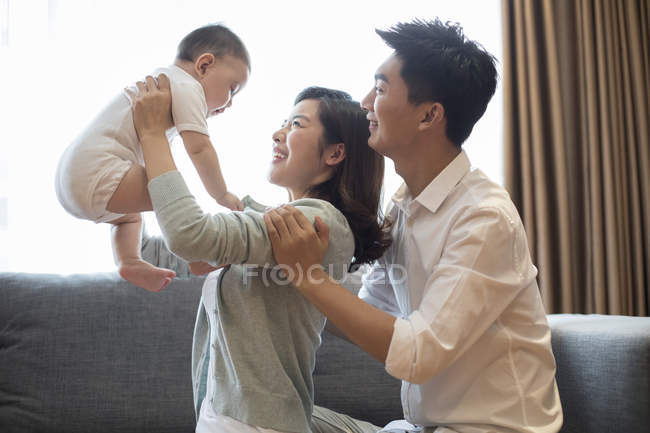 Parents chinois soulevant bébé garçon à la maison — Photo de stock