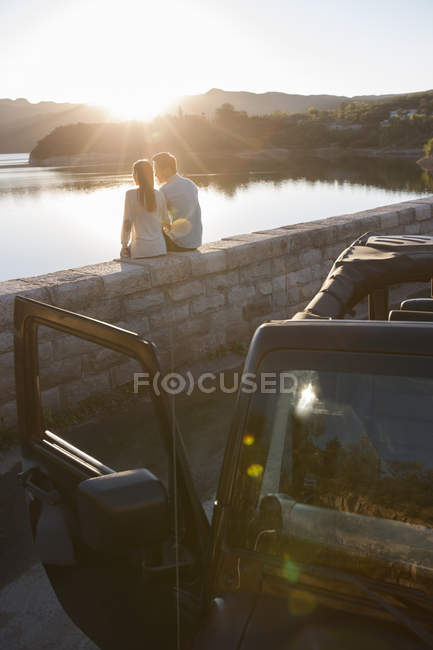 Pareja china sentada junto al lago en los suburbios - foto de stock
