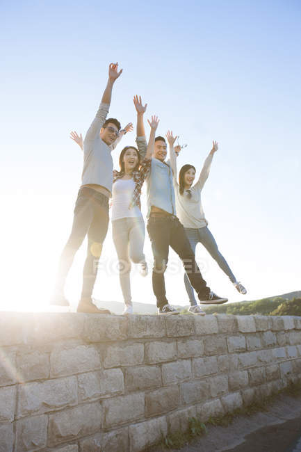 Chinese friends posing in suburbs with arms raised — Stock Photo