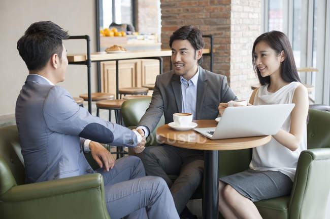 Negócios asiáticos apertando as mãos enquanto se encontram no café — Fotografia de Stock