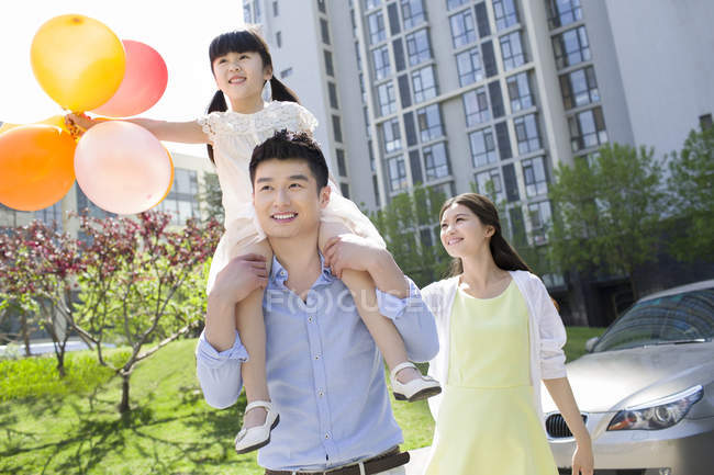 Familia china feliz caminando en el parque con globos - foto de stock