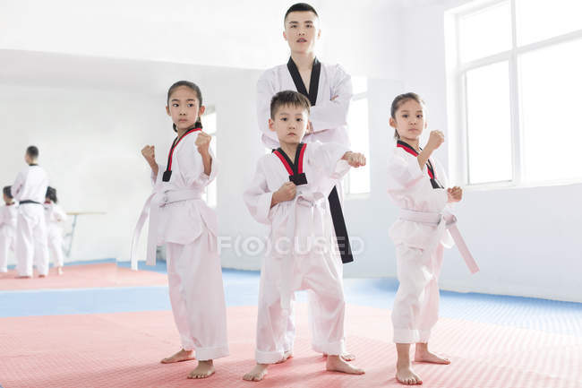 Instructor chino posando en sala de ejercicios con estudiantes de Taekwondo - foto de stock