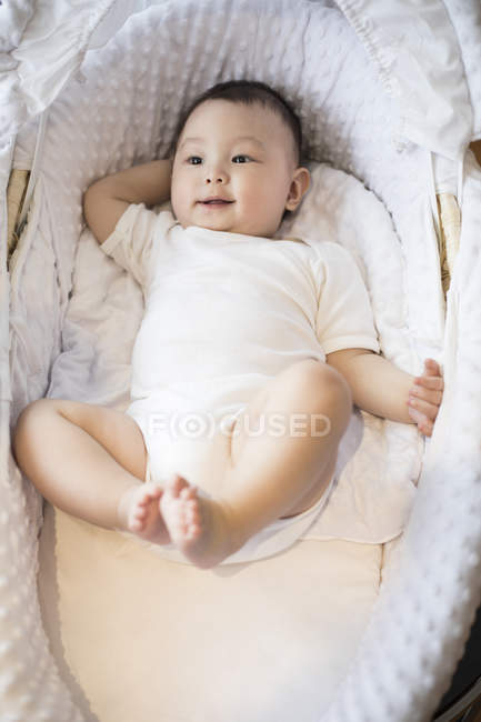 Lindo bebé chino acostado en la cesta de Moisés - foto de stock