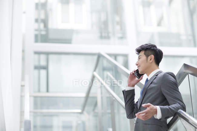 Hombre de negocios chino hablando por teléfono en el edificio de oficinas - foto de stock