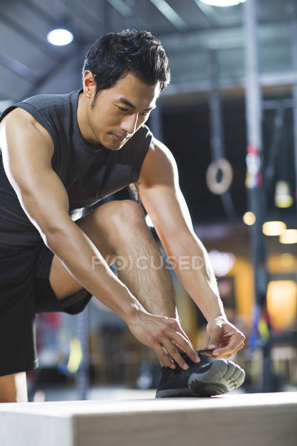 Asiatischer Athlet bindet Schnürsenkel in Turnhalle — Stockfoto