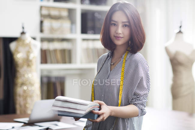Portrait of female asian fashion designer holding samples — Stock Photo