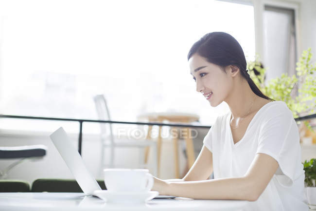 Femme chinoise utilisant un ordinateur portable dans un café — Photo de stock