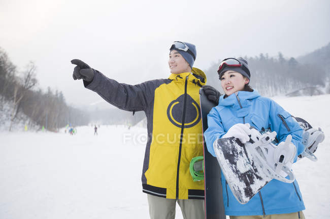 Casal chinês de snowboarders em pé na encosta — Fotografia de Stock