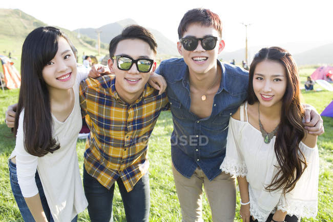 Chinese friends embracing and looking in camera at festival camping — Stock Photo