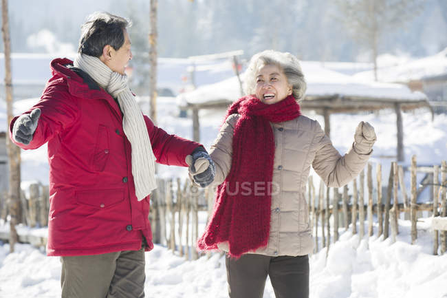 Chinese senior couple holding hands while walking outdoors — Stock Photo