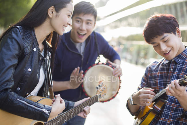 Chinese friends playing musical instruments on street — Stock Photo