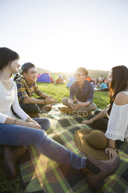 Chinese friends sitting on blanket at music festival — Stock Photo