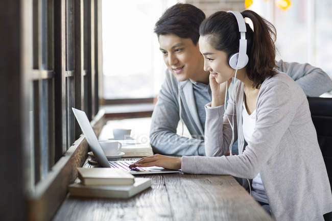 Chinês homem e mulher em fones de ouvido usando laptop no café — Fotografia de Stock