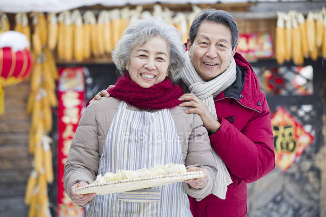 Senior couple holding dish of traditional dumplings — Stock Photo