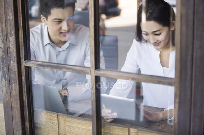Homem e mulher chineses usando tablet digital no café — Fotografia de Stock