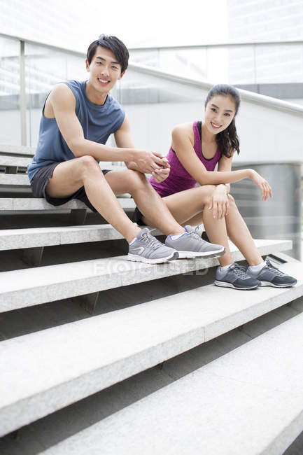 Chinese couple resting on stairs after exercising — Stock Photo
