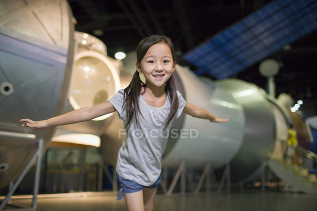 Chinese girl posing with arms outstretched in museum — Stock Photo