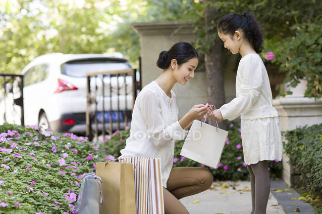 Madre e hija chinas mirando en la bolsa de compras - foto de stock