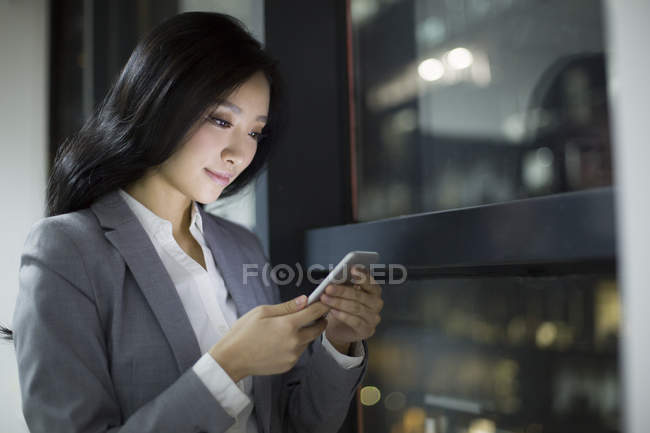 Empresaria china usando teléfono inteligente en la oficina - foto de stock