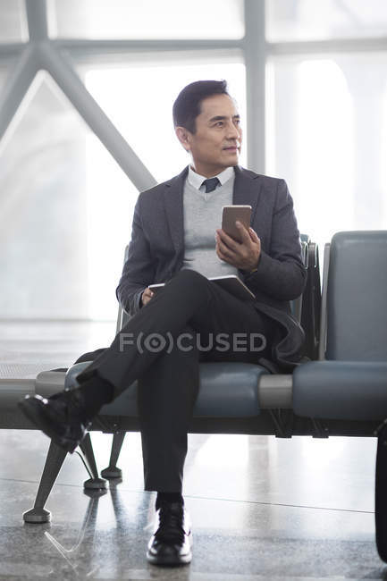 Азіатських людині проведення смартфон в аеропорту — стокове фото