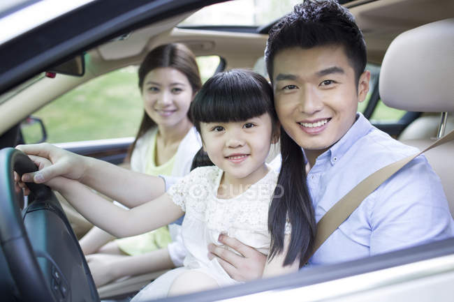 Pareja china con hija sentada en coche - foto de stock