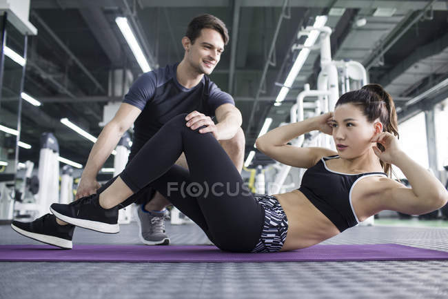 Mujer asiática trabajando con entrenador en gimnasio - foto de stock