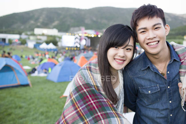 Chinese couple wrapped in blanket embracing at festival camping — Stock Photo