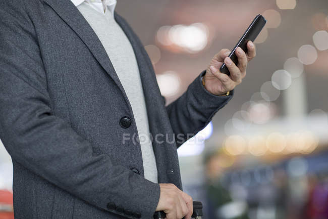 Чоловік тримає смартфон в аеропорту — стокове фото