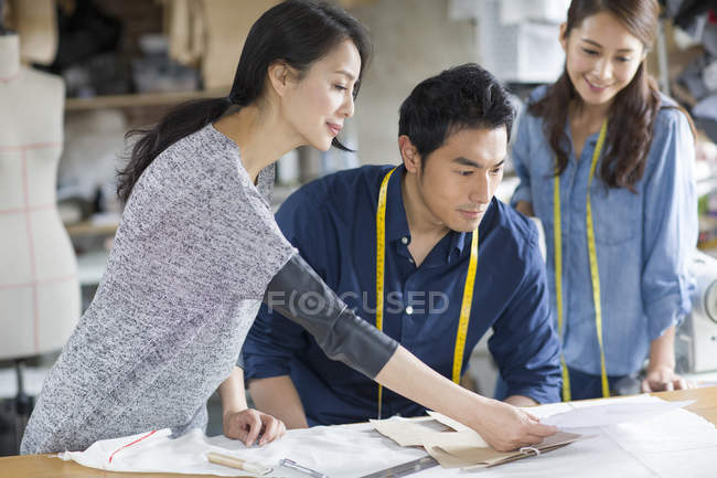 Chinese fashion designers looking at sketch in studio — Stock Photo