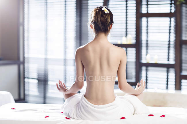 Visão traseira da jovem mulher meditando envolto em toalha — Fotografia de Stock