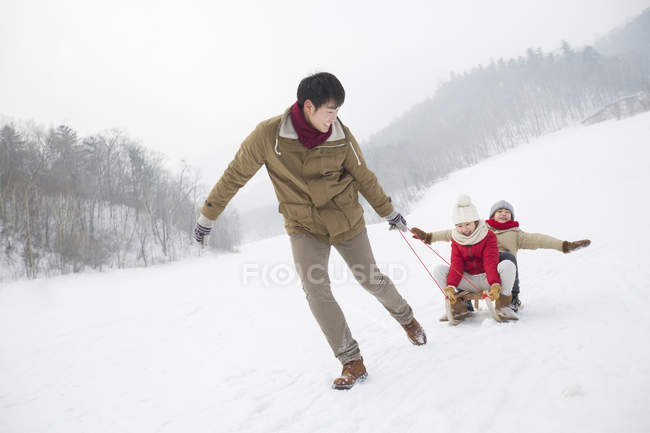 Chinesischer Vater zieht Kinder auf Schlitten — Stockfoto