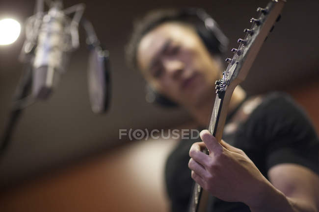 Homem chinês tocando guitarra no estúdio de gravação — Fotografia de Stock