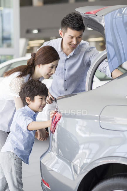 Chinese family examining new car trunk in showroom — Stock Photo