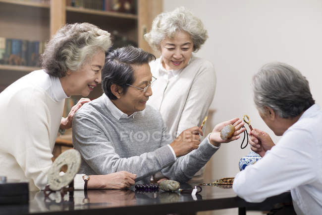Amigos chinos mayores admirando antigüedades - foto de stock