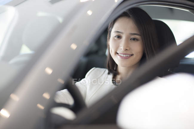 Chinese woman sitting in car on parking lot — Stock Photo