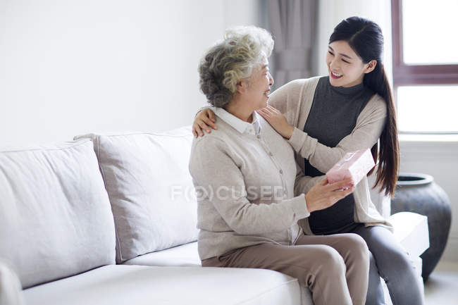 Chinese daughter cheering up mother with gift box — Stock Photo