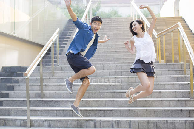 Casal chinês pulando em degraus de rua — Fotografia de Stock