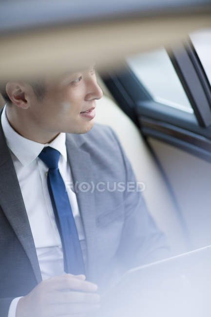 Chinese businessman sitting on car back seat — Stock Photo