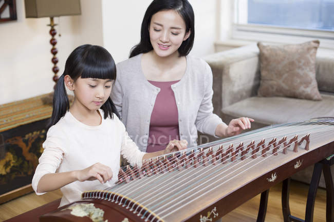 Mãe chinesa ensinando filha tradicional instrumento musical zither — Fotografia de Stock