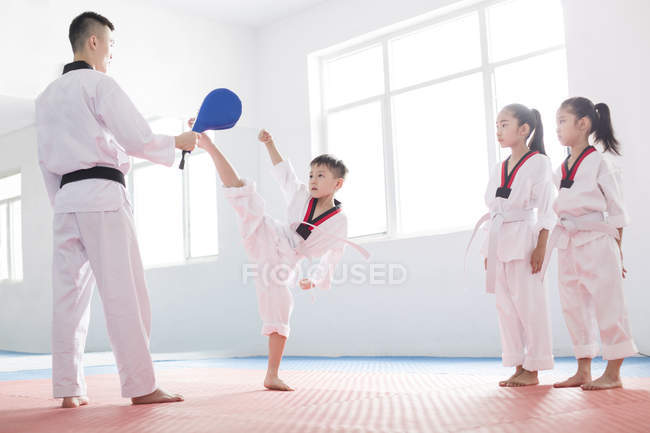 Niños chinos haciendo ejercicio con instructor de Taekwondo - foto de stock