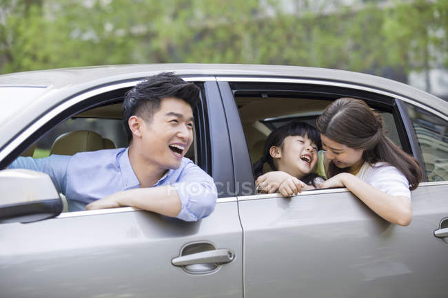 Familia china montando en coche y riendo - foto de stock