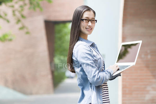 Chinese woman holding laptop on street — Stock Photo