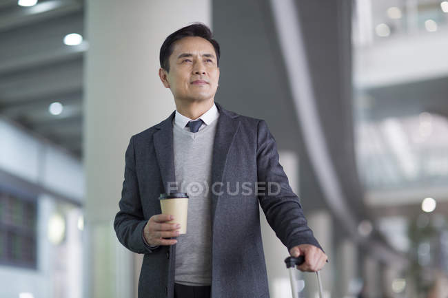 Азиатский мужчина ждет с кофе в аэропорту — стоковое фото
